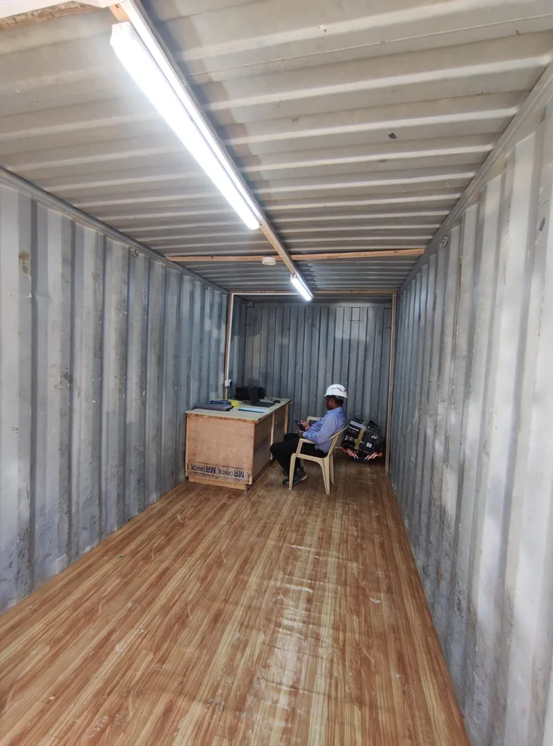 Site office set up inside a container, with a desk, laptop and TMI engineer