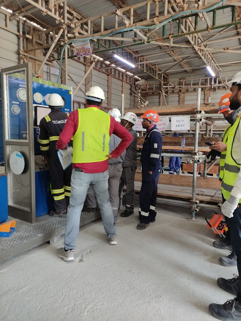TMI technician running a safety valve pop-up test on the mobile test unit at a customer site, with client inspectors watching